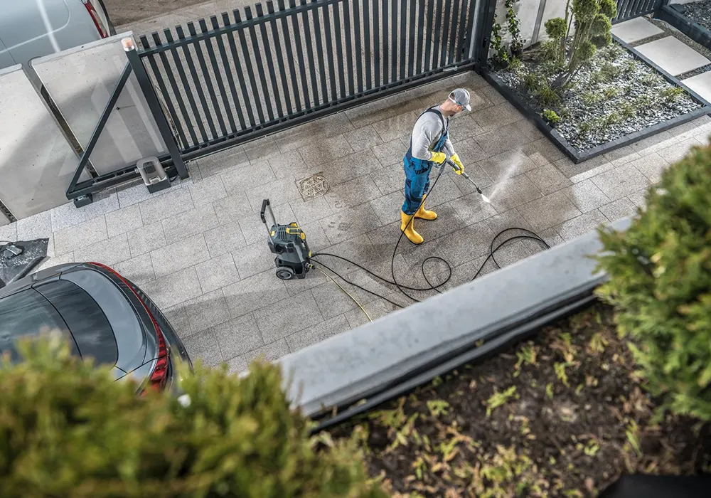 High-angle view of a technician pressure washing a modern concrete paver driveway by ASC Painting Corp.