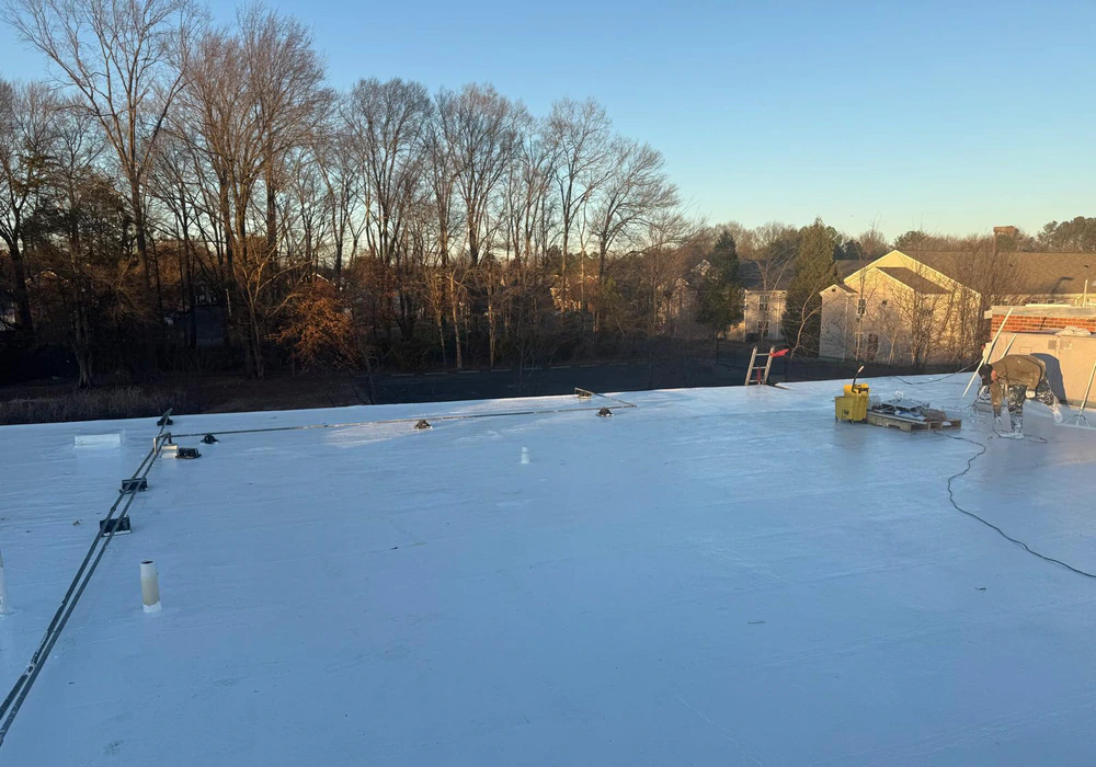 ASC Painting crew waterproofing a large flat roof with white coating