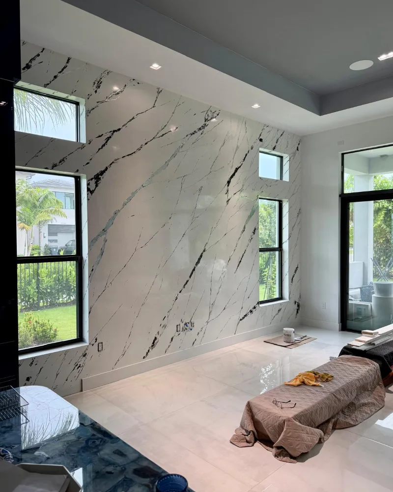 After: the same wall finished in white marble-effect Venetian Plaster with dark veining